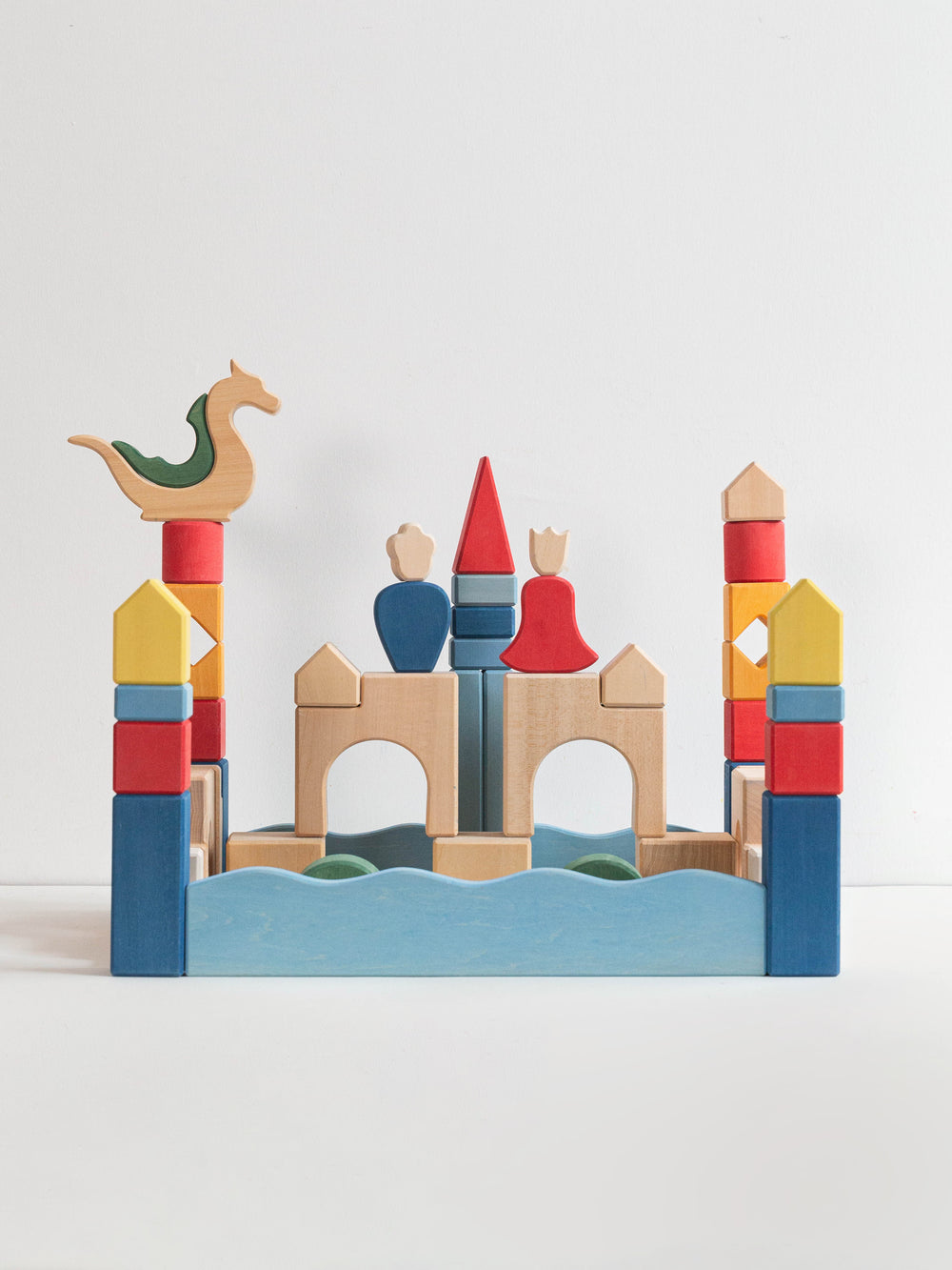 Colorful toy castle with dragon, king, queen and castle on a white background