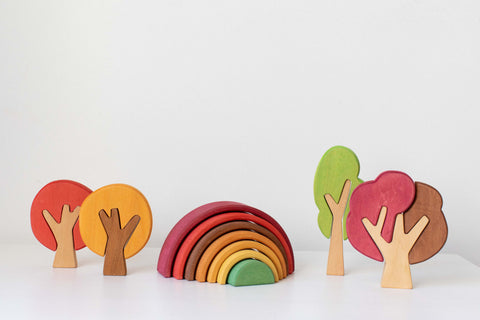 Wooden toys featured in yellow, red, green and brown trees, and rainbow on the white  background