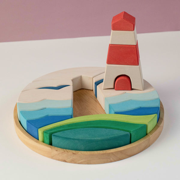 Lighthouse Puzzle Block with red and white tower, layered blue waves and green curved pieces in a round tray