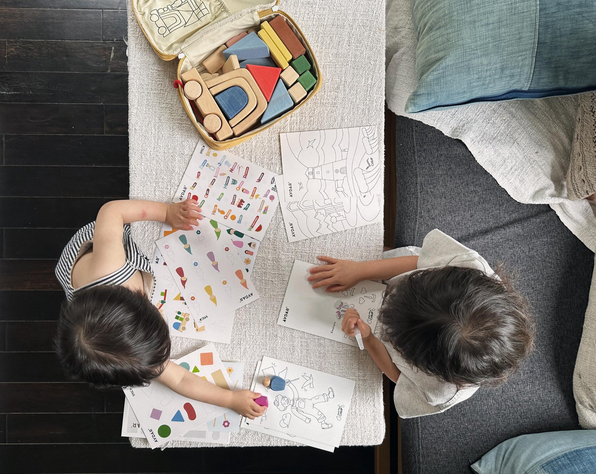 The Lodge and Trailer sets come with an envelope filled with coloring pages, drawing sheets, and playful stickers — perfect travel activities for kids on airplanes or long train rides. Inside, kids discover eco-friendly wooden tblocks, simple geometric shapes, little cars, arches, and wooden dolls. They can build, invent stories and enjoy the tactile feel of natural wood.