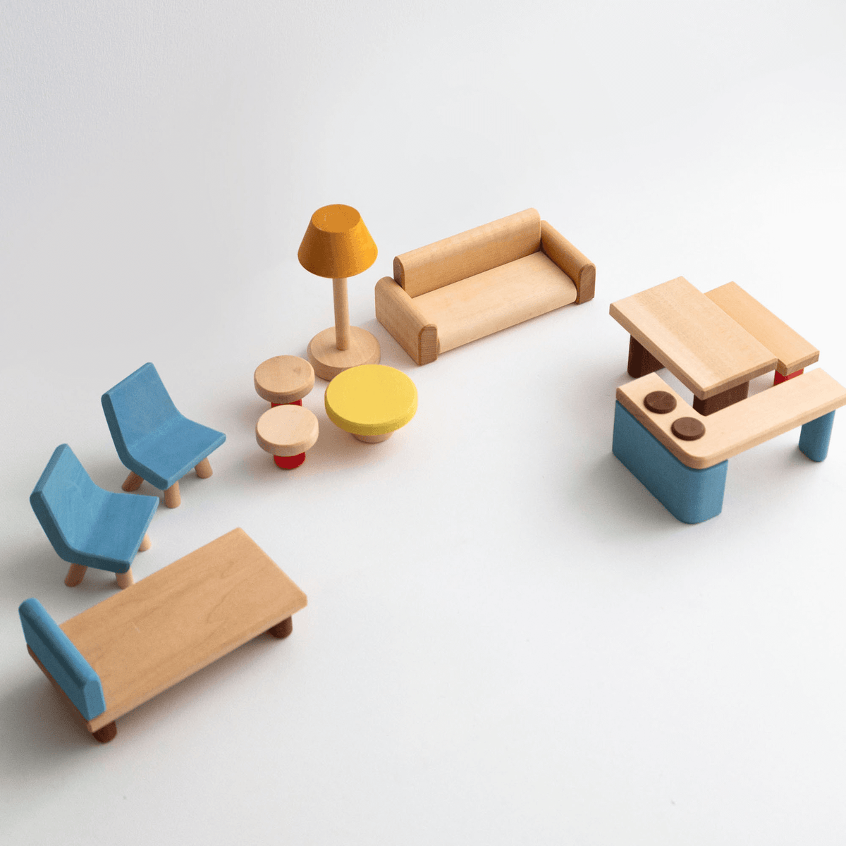 A collection of wooden dollhouse furniture including a bed, table, kitchen counter, sofa, two chairs, stools, and a bench, with a natural wood finish and some painted details.