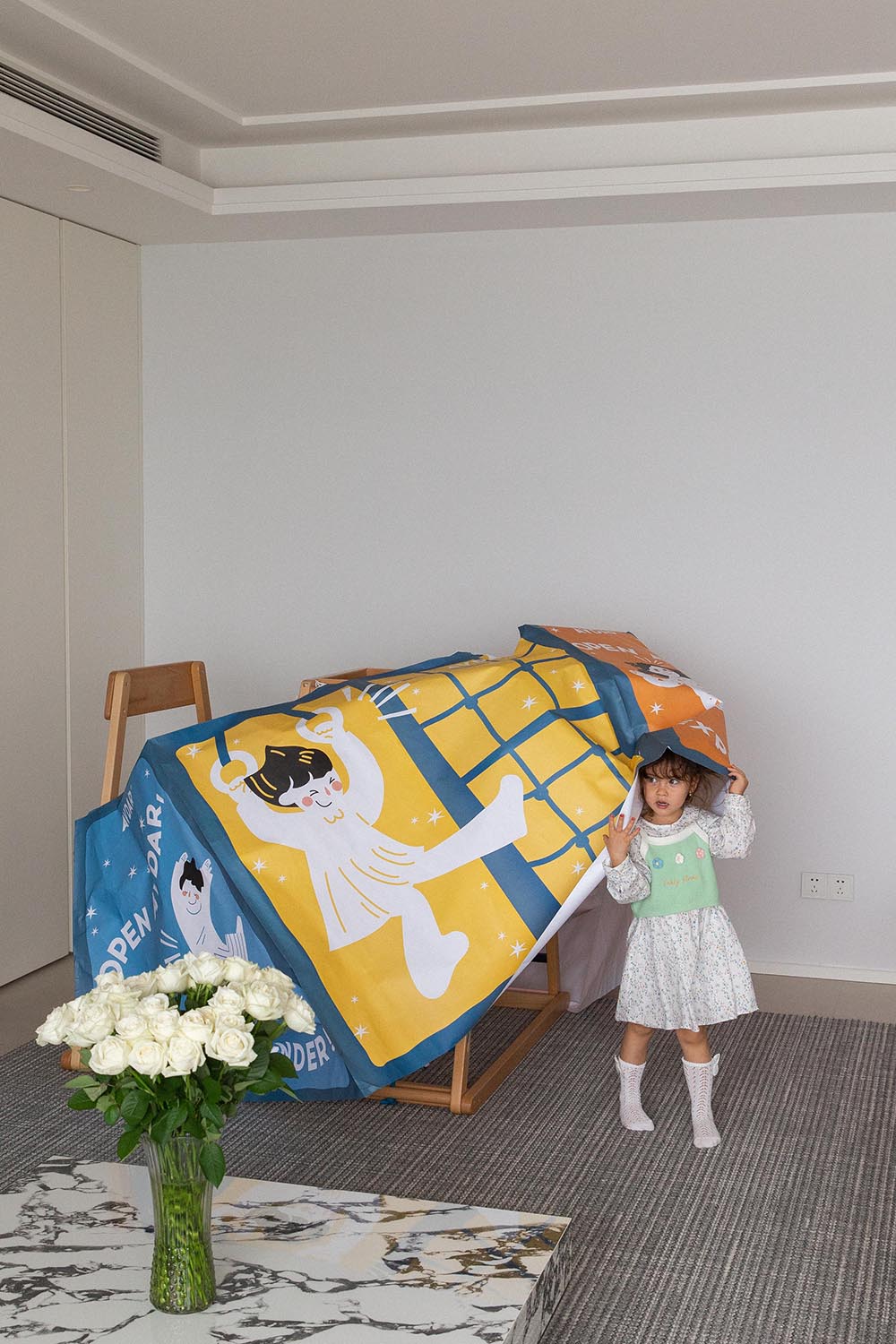 A girl opens posters of the tent with illustrations of a child and text on a white background.