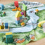 Close-up of wooden figures, boat, bridges and houses arranged on the Kingdom Valley play cloth