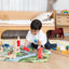 Child building a wooden block kingdom on the Kingdom Valley play cloth