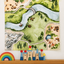 Kingdom Valley play cloth displayed on a wall above colorful wooden blocks and a rainbow