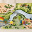 Kingdom Valley play cloth staged with wooden trees, houses, figures, a boat and a rainbow