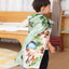 A child explores the Kingdom Valley play cloth as a cape, small-world play mat and imaginative backdrop with wooden toys.