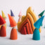 A set of colorful wooden peg dolls with different colored hats, standing around a wooden fire