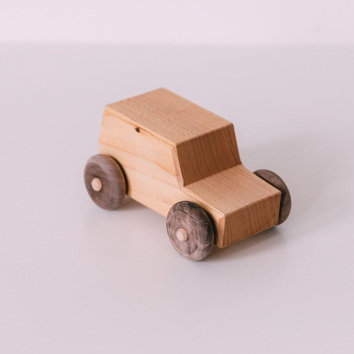 A small wooden toy jeep with a beige finish and dark gray wheels, displayed on a white background.