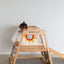 A child playing on a wooden climbing frame from the wooden ladder