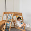 A child playing on the swing of the wooden climber