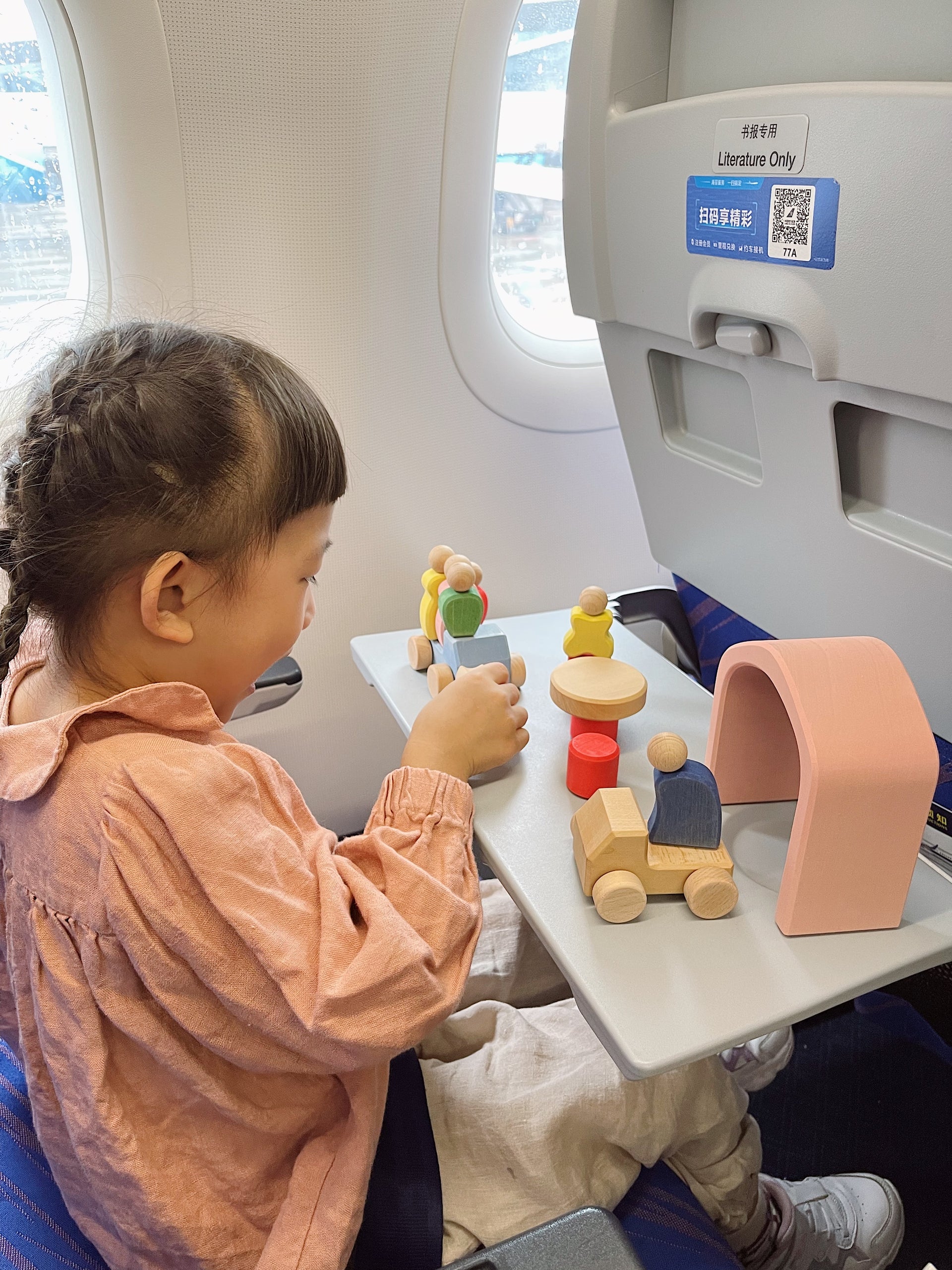 Young children can use portable wooden building blocks as companions during flights to alleviate boredom and reduce travel stress.