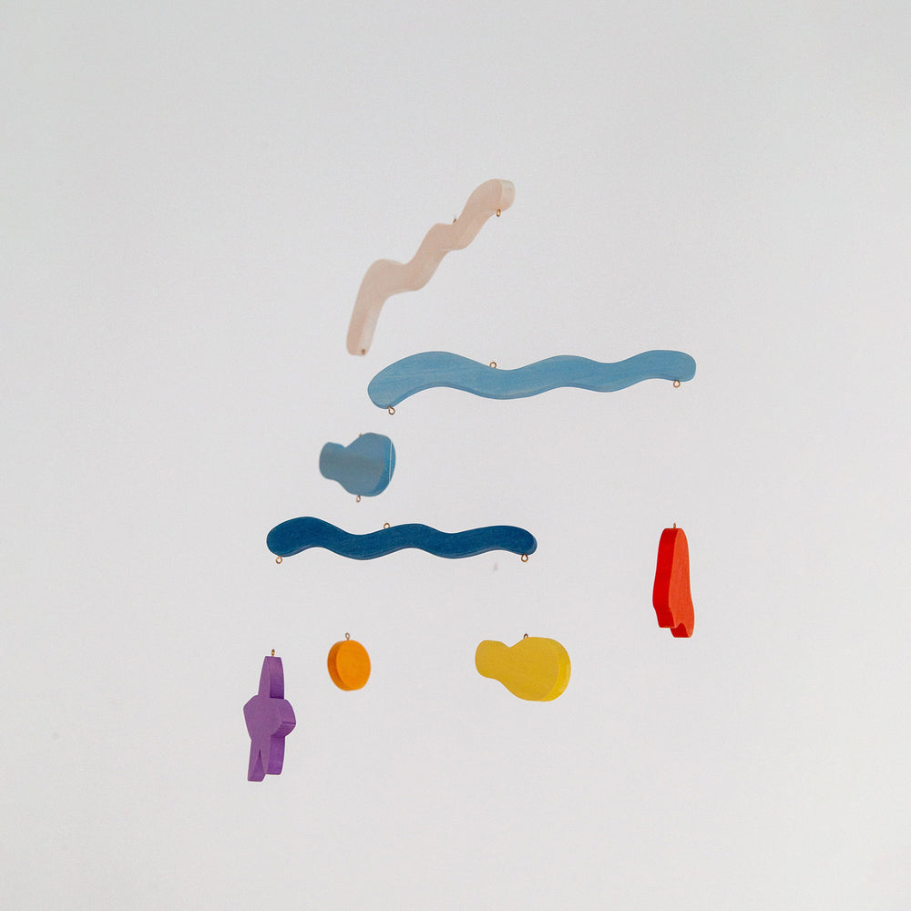 A colorful mobile toy with marine-themed shapes including what appears to be a whale and a boat, against a white background.