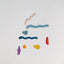 A colorful mobile toy with marine-themed shapes including what appears to be a whale and a boat, against a white background.