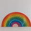 A colorful wooden rainbow stacker toy with multiple arches in various sizes arranged in a spiral pattern on a white background.