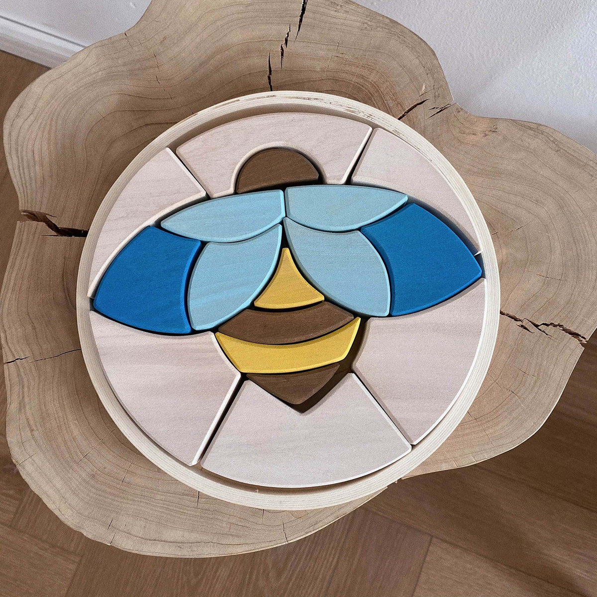 Bee Puzzle Block with blue, yellow and brown wooden pieces arranged in a round tray
